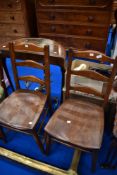 A pair of traditional solid seat ladder back kitchen chairs