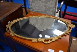 A gilt metal wall mirror having scroll decoration