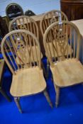 A set of four beech frame wheel back kitchen chairs