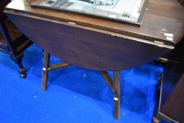 An Ercol dark elm drop leaf dining table, lacking label