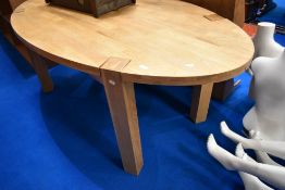 A modern light wood oval dining table on chunky legs