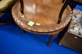 A vintage circular coffee table having carved foliate decoration and pie type edge