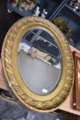 A large Victorian oval bevel edged mirror with a gilt and gesso frame. 95cm x 70cm
