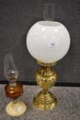 Two early 20th century oil burning lamps including a polished brass with milk glass globe shade.