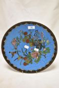 A Japanese Cloisonne charger plate decorated with birds and flowers on a blue ground.