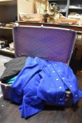 A large assortment of retro and vintage textiles with a large purple suitcase.