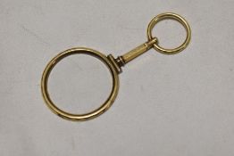 An early 20th century hand held monocle having yellow metal body with hooped grip.