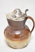 An antique Doulton style stone ware hunting scene jug having HM silver rim and lid.