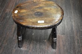 An antique oak stool on turned legs.