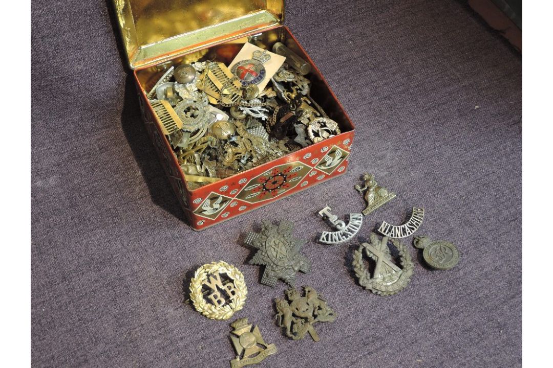 A tin box of mainly military Cap Badges including Cameron, Military Police, Manchester, Royal