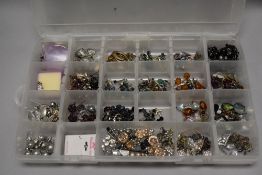 A compartment tray containing mainly white metal ear rings and small trinkets.