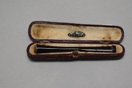 A cased red bakelite cigarette holder having rose gold tip.