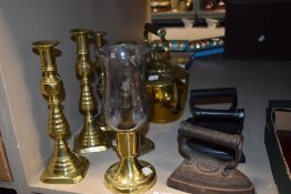 Two pairs of brass candlesticks with an oil lamp, stove kettle and three irons.