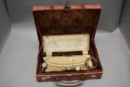 A jewellery case containing three wristwatches and a string of simulated pearls.