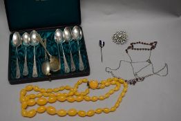 A cased set of Scottish themed tea spoons with a selection of brooches.