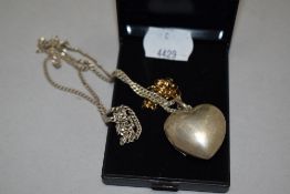 A silver heart shaped locket with white metal chain.