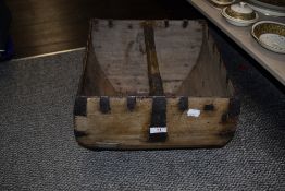 An antique primitive form wooden trug basket with metal braces and a central handle.
