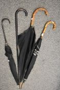 Three vintage umbrellas two having bamboo handles also one walking stick.