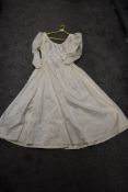 A circa 1988 wedding dress, having pink and silver embroidered detailing and bead work.