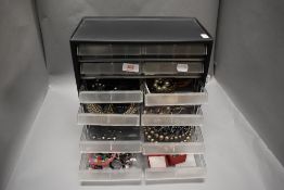 A compartmental case full of costume jewellery including necklaces, bracelets, earrings and semi