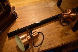 A vintage lighting track with three copper effect spots