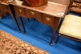 A Georgian oak lowboy having three drawers , brass drop handles and shaped apron
