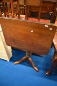 A Victorian mahogany pedestal table having rectangular flip top with turned column and triple