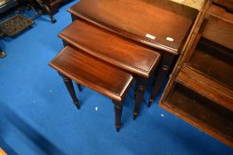 A reproduction mahogany nest of three tables