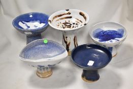 Five studio pottery pedestal bowls in blue and white glazes.