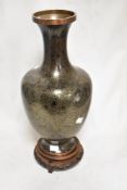 A Japanese Cloisonne enamel vase having black ground, with yellow metal wire. On carved wooden base.