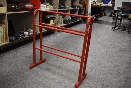 A Victorian towel rail having been painted gloss red.
