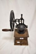 A vintage coffee mill with wooden base, appears to be missing a cog.