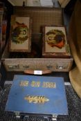 A small sized childrens suitcase with a selection of advertising tins and boxes.