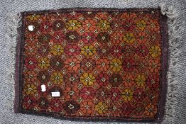 A vintage hand woven Afghan wool rug in red and brown grounds with a floral pattern with fringing