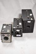 Three early 20th century photographic cameras including Ensign, Kodak and Brownie.