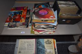 A shelf of 75rpm vinyl singles and records with a selection of related ephemera.