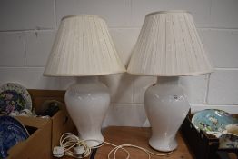 A pair of large ceramic vases in white with circular pleated shades.