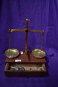 An early 20th century chemist or apothecary class B scale set mounted on mahogany draw with weight