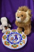 Two stuffed toys one a lion and one Snoopy and a colourfully decorated medeteranian style plate
