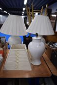 Three large ceramic vases in white two with circular pleated shades and one square shade.