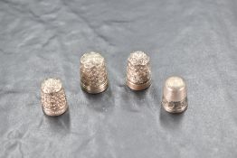 A group of three silver thimbles, of traditional form and sold together with a white metal example