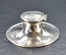 A George V silver Capstan inkwell, of spreading circular form with hinged cover and reeded