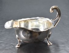 A George V silver gravy boat, of traditional design having generous spout opposed by double scroll