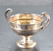 A George V silver trophy, having two scrolled handles enclosing the dished cylindrical body with