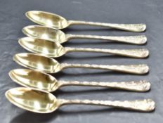 A set of six Victorian silver gilt dessert spoons, the handles having scroll and shell terminals