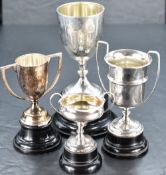 A group of four silver trophies, various dates, makers and designs, each with ebonised socle,