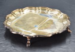 A George V silver salver of circular form with Chippendale design moulded rim, raised on three