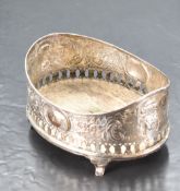 A 19th century white metal coaster, of oval form form with moulded rim and profuse embossed