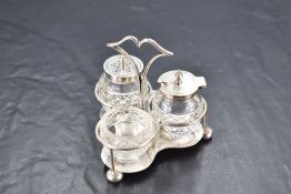 An Edwardian silver and cut-glass condiment set, having a raised and shaped central handle over