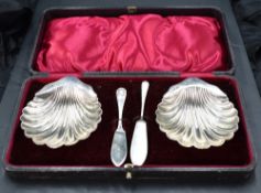 A cased pair of late Victorian silver butter dishes, of scallop shell form with shaped lip handle